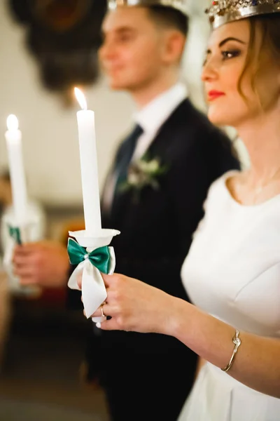 Novia y novio sosteniendo velas en la iglesia — Foto de Stock