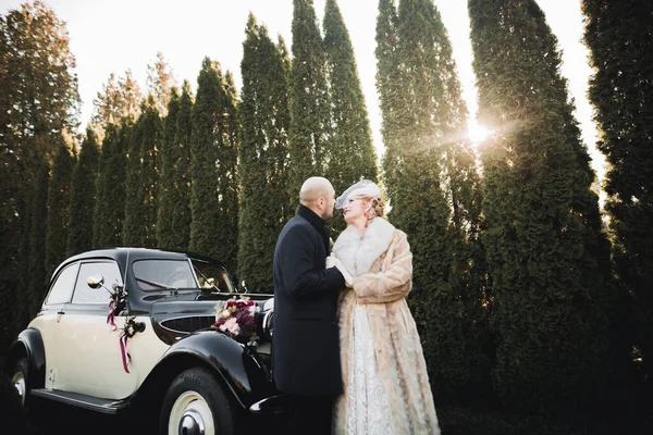 Heureux couple nouvellement marié, homme et femme embrasser près de voiture rétro élégant — Photo