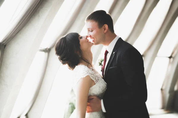 Lovely happy wedding couple, bride with long white dress posing in beautiful city — Stock Photo, Image