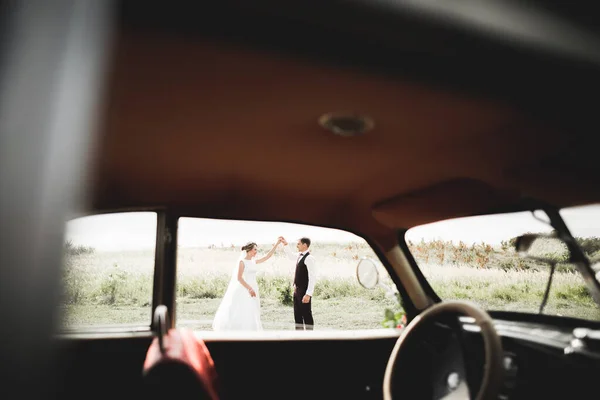 Felice coppia di sposi, uomo e moglie baciare vicino elegante auto retrò — Foto Stock