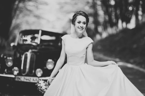Underbar elegant brud poserar nära snygg retro svart bil Lyx bröllop i vintage stil. Porträtt — Stockfoto