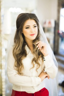 Cüppeli muhteşem gelin bir odada düğün töreni için poz veriyor ve hazırlanıyor.