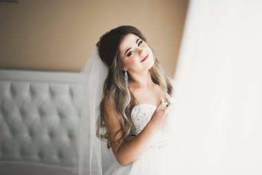 Beyaz elbiseli lüks gelin düğün törenine hazırlanırken poz veriyor.