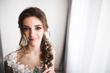 Beyaz elbiseli lüks gelin düğün törenine hazırlanırken poz veriyor.