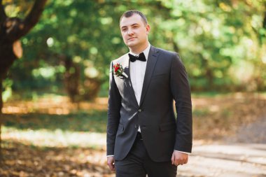 Yaka çiçeğiyle poz veren mutlu yakışıklı damat.
