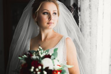 Çekici gelinin portresi, uzun saçlı, büyük buketli poz veren.