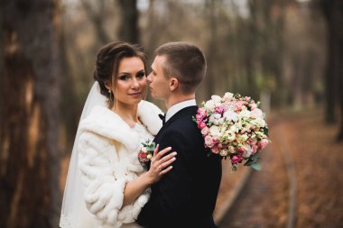 Güzel, genç bir çift ellerinde çiçeklerle poz veriyorlar.