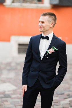 Yaka çiçeğiyle poz veren mutlu yakışıklı damat.