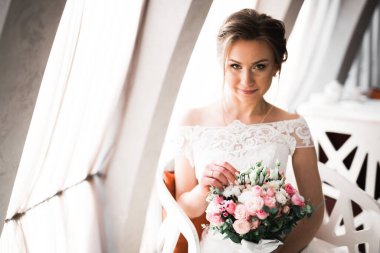 Çekici gelinin portresi, uzun saçlı, büyük buketli poz veren.