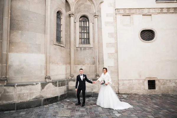 Düğün fotoğrafı çekimi. Gelin ve damat şehirde yürüyorlar. Birbirlerine sarılıp bakan evli bir çift. Tutma buketi — Stok fotoğraf