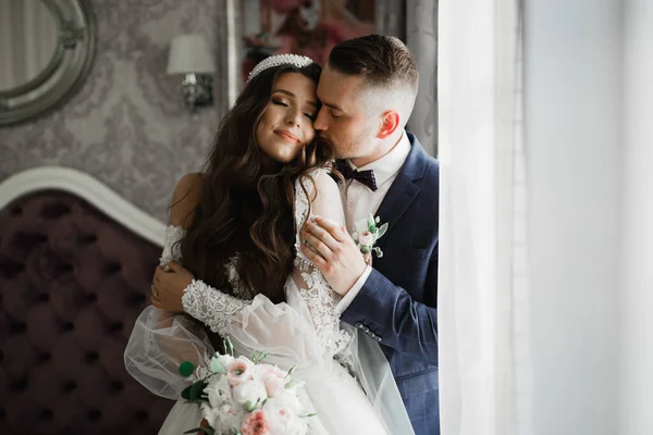 Beautiful young wedding couple posing with bouquet of flowers in hands — Stock Photo, Image