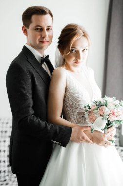 Güzel, genç bir çift ellerinde çiçeklerle poz veriyorlar.