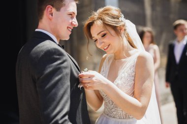 Güzel gelin damat elbisesinde güllerle yaka çiçeği takıyor