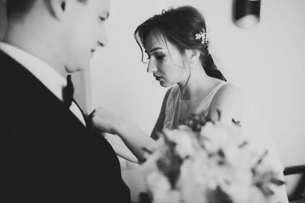 Красива наречена одягає бутоньєрку з трояндами на костюмі нареченого — стокове фото