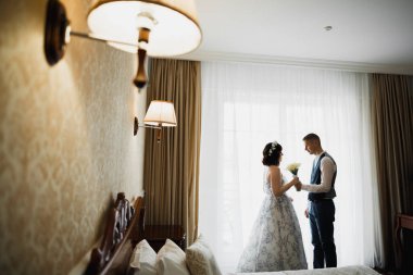 Güzel gelin ve damat düğün günlerinde kucaklaşıp öpüşürler.