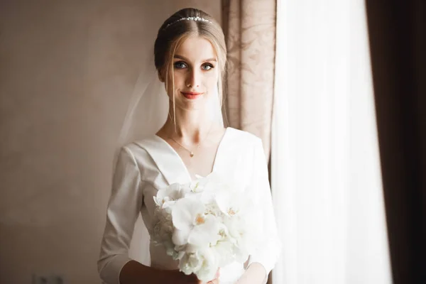 Portrét ohromující nevěsty s dlouhými vlasy pózující s velkou kyticí — Stock fotografie