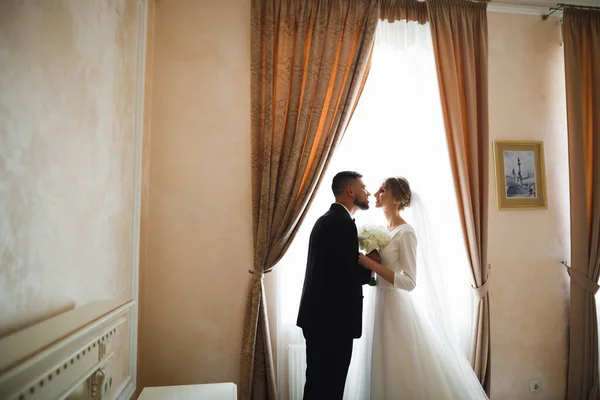 Vacker brud och brudgum omfamnar och kysser på sin bröllopsdag — Stockfoto