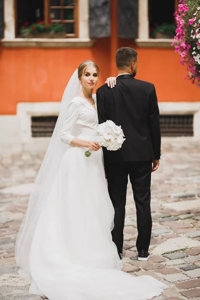 Vackra unga bröllop par poserar med bukett blommor i händerna — Stockfoto