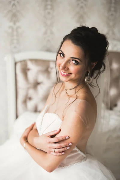 Preciosa novia en bata posando y preparándose para la ceremonia de boda cara en una habitación —  Fotos de Stock