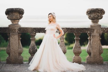 Şatonun yanında duran zarif beyaz elbiseli, güzel esmer gelin.