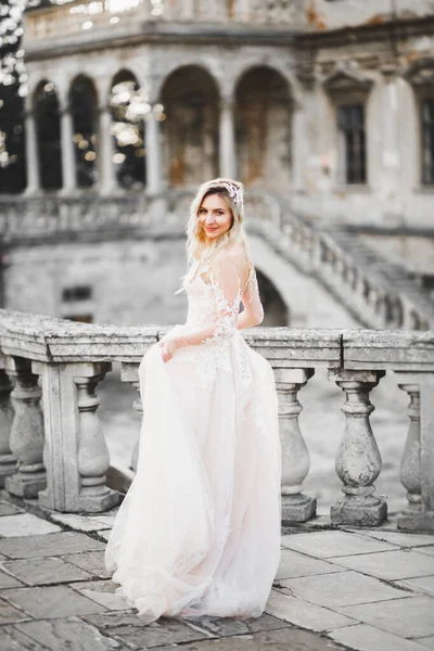 美しいですブルネット花嫁でエレガントな白いドレス保持花束近くの城 — ストック写真