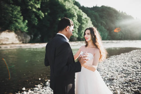 Düğün çifti, damat ve gelin kucaklaşıyor, nehir kenarında. — Stok fotoğraf