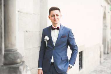 Yaka çiçeğiyle poz veren mutlu yakışıklı damat.