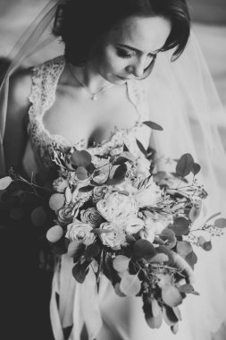 Cüppeli muhteşem gelin bir odada düğün töreni için poz veriyor ve hazırlanıyor.