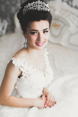 Cüppeli muhteşem gelin bir odada düğün töreni için poz veriyor ve hazırlanıyor.