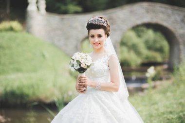 Çekici gelinin portresi, uzun saçlı, büyük buketli poz veren.