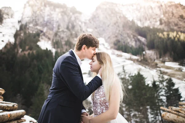 若い幸せなカップルキス、背景に雪の中の山の風景 — ストック写真