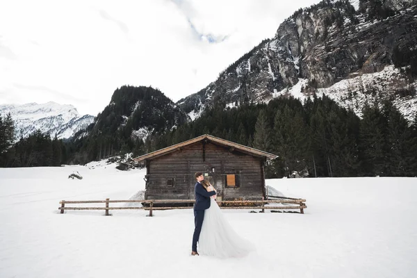 Schönes junges Paar in den Winterbergen. Winterwanderung der Verliebten. Mann umarmt Frau — Stockfoto