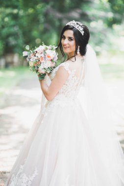 Parkta poz veren gelinlikli güzel, lüks bir gelin.