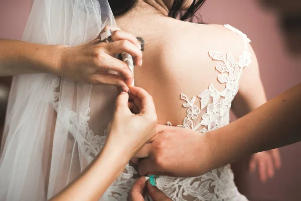 Hermosa novia con vestido de novia de moda con plumas con maquillaje de lujo deleite y peinado, estudio sesión de fotos interior — Foto de Stock