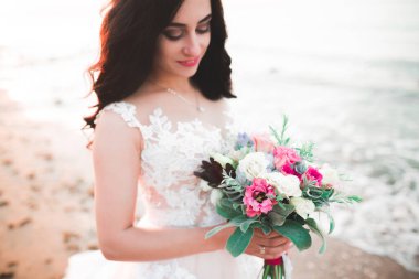 Gelin çiçekli büyük ve güzel bir düğün buketi tutuyor.