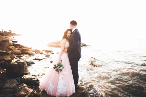 Hochzeitspaar küsst und umarmt sich auf Felsen nahe blauem Meer — Stockfoto