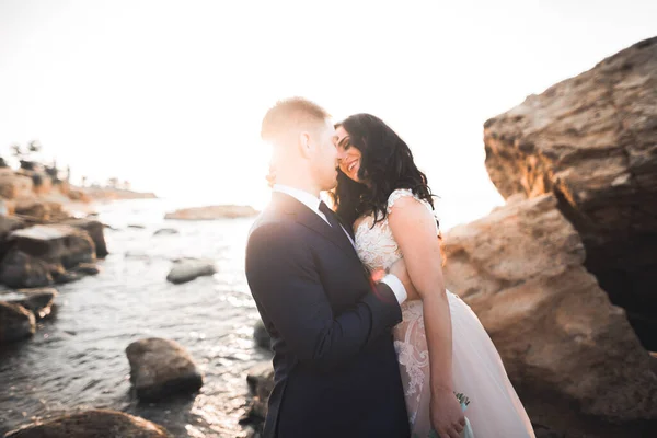 Boda pareja, novio, novia con ramo posando cerca del mar y el cielo azul — Foto de Stock