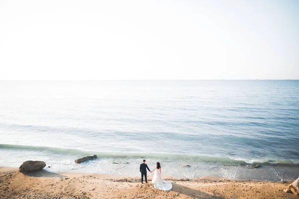 Boda pareja besándose y abrazándose en rocas cerca de mar azul — Foto de Stock