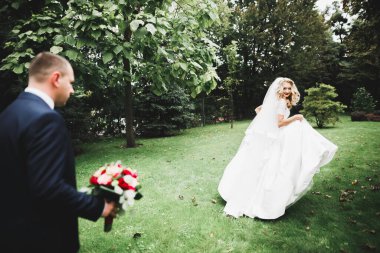 Yeni evli çift el ele tutuşurken parkta koşup zıplıyorlar.