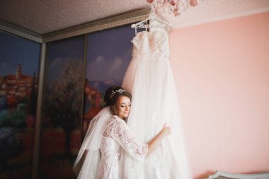 Cüppeli muhteşem gelin bir odada düğün töreni için poz veriyor ve hazırlanıyor.