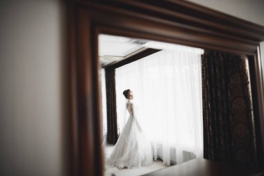 Cüppeli muhteşem gelin bir odada düğün töreni için poz veriyor ve hazırlanıyor.