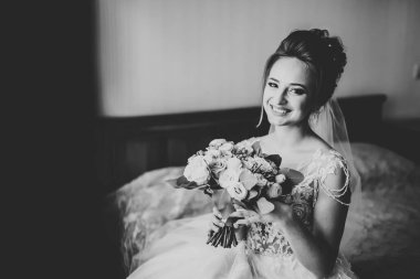 Cüppeli muhteşem gelin bir odada düğün töreni için poz veriyor ve hazırlanıyor.