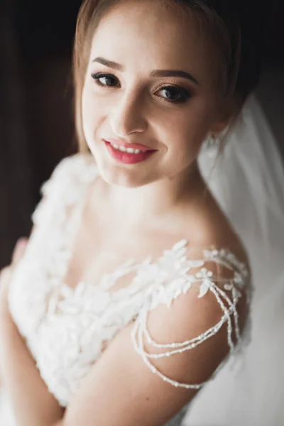 Preciosa novia en bata posando y preparándose para la ceremonia de boda cara en una habitación — Foto de Stock