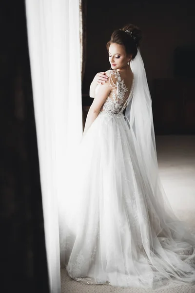 Preciosa novia en bata posando y preparándose para la ceremonia de boda cara en una habitación —  Fotos de Stock