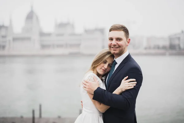 Hermosa novia posando para el novio y divertirse, cerca del parlamento de Budapest, espacio para el texto, pareja de boda —  Fotos de Stock