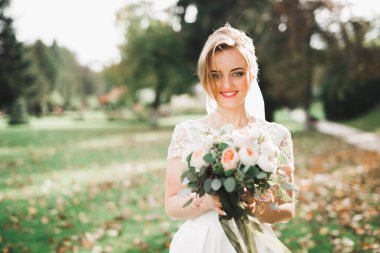 Gelin çiçekli büyük ve güzel bir düğün buketi tutuyor.