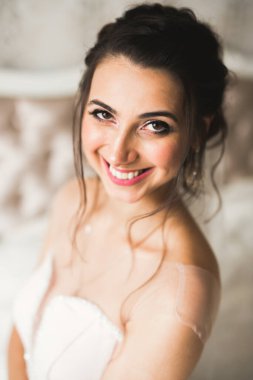 Cüppeli muhteşem gelin bir odada düğün töreni için poz veriyor ve hazırlanıyor.