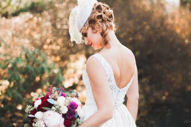 Gelin çiçekli büyük ve güzel bir düğün buketi tutuyor.