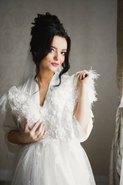 Beyaz elbiseli lüks gelin düğün törenine hazırlanırken poz veriyor.