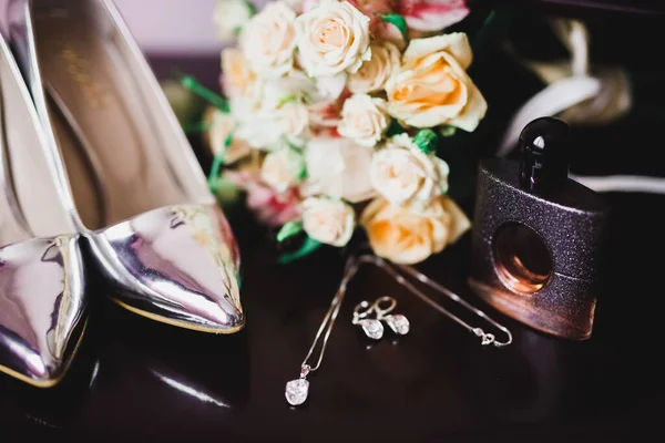 Bruiden bruiloft schoenen en kostuum sieraden met een boeket met rozen en andere bloemen. — Stockfoto